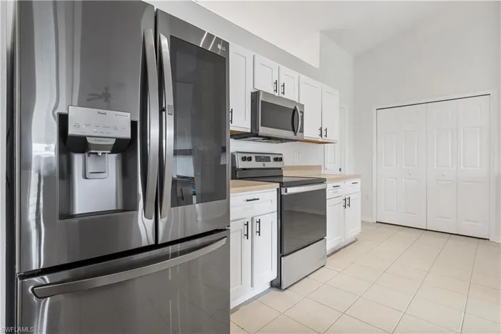 Kitchen featuring light tile flooring, white cabinetry, and appliances with stainless steel finishes