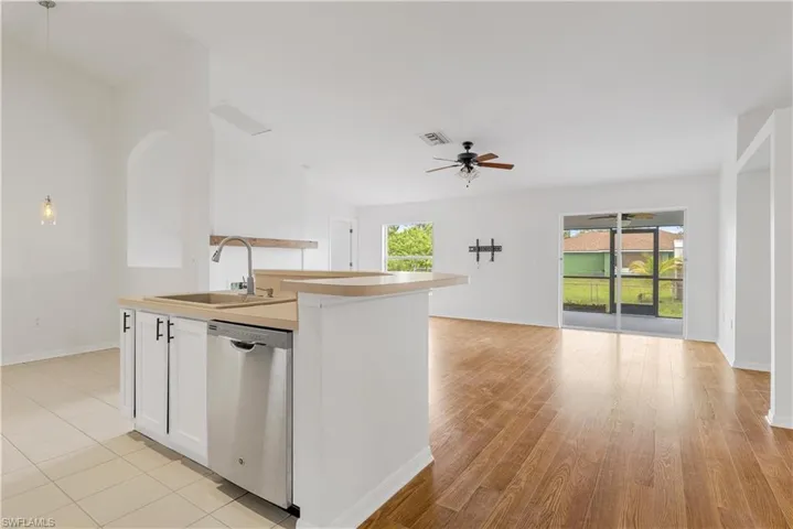 Kitchen with white cabinetry, light hardwood / wood-style flooring, stainless steel dishwasher, sink, and ceiling fan