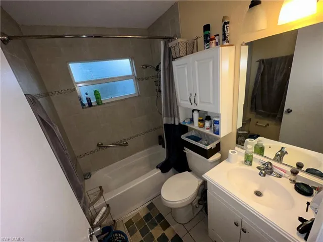 Full bathroom with tile patterned flooring, toilet, shower / bathtub combination with curtain, and vanity