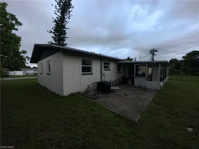 Rear view of property with a sunroom, a patio, cooling unit, and a yard