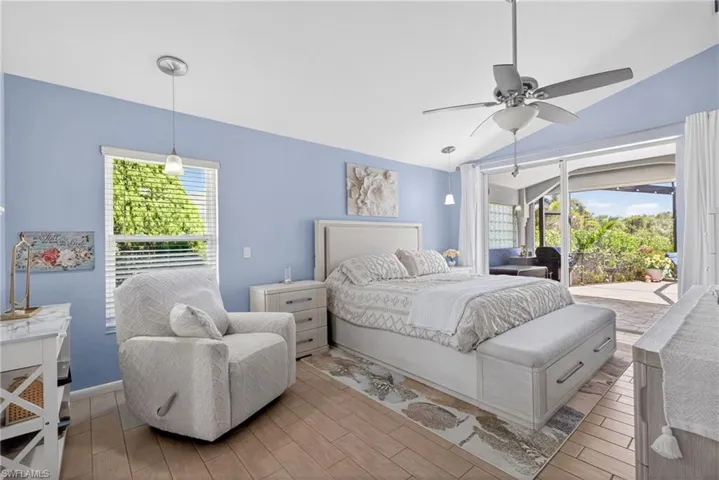 Vaulted ceiling with a ceiling fan, wood-finish flooring, built-in storage bench, sliding glass door, and a dedicated outdoor patio