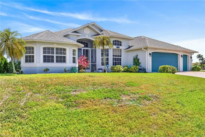 Single-story residence featuring a gray shingle roof, arched transom windows, screened entry, and an attached two-car garage with teal doors
