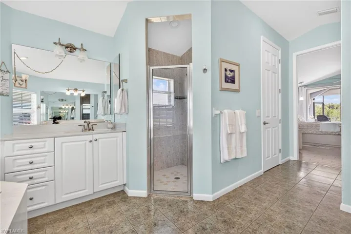 Bathroom featuring a single vanity with white cabinetry, light-toned countertop, and an expansive mirror