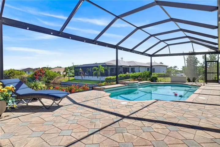 Screened-in outdoor living space featuring a swimming pool, integrated spa, and paver patio