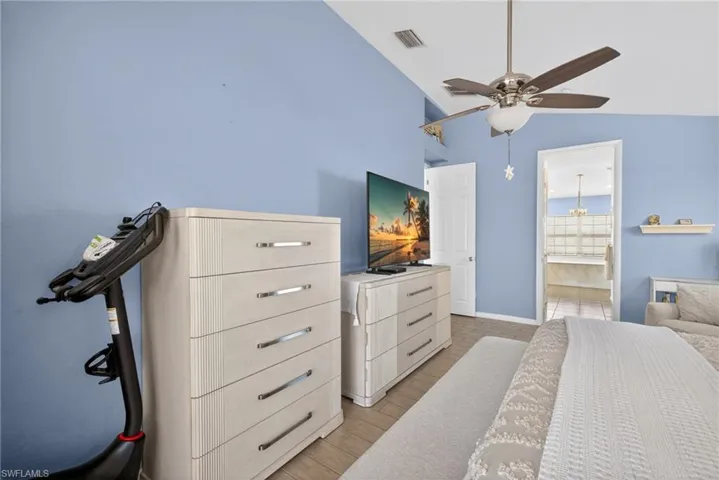 High ceilings, ceiling fan with integrated lighting, tiled flooring, built-in wall shelving, and an open doorway to an adjoining space