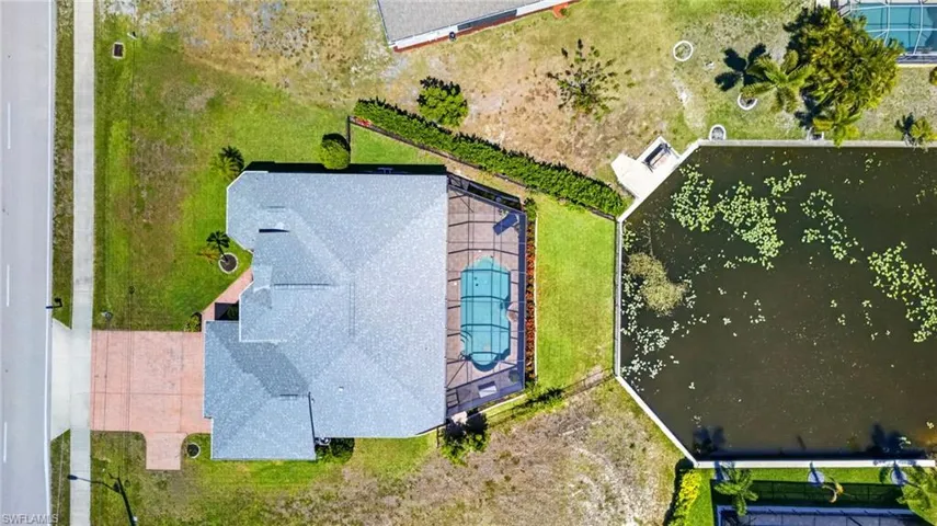 Shingled roof residence featuring a screened-in pool, waterside patio, and direct water frontage