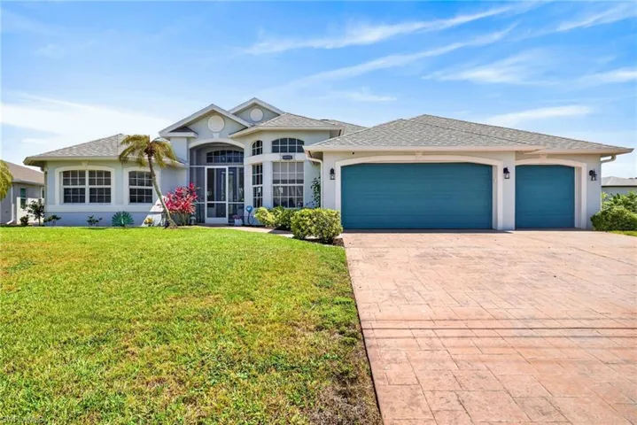 Expansive stamped concrete driveway with a two-car garage and a single-car garage featuring teal doors