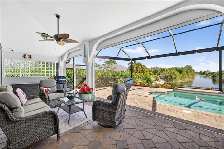 Screened-in patio with geometric paver flooring, ceiling fan, and a built-in outdoor grill