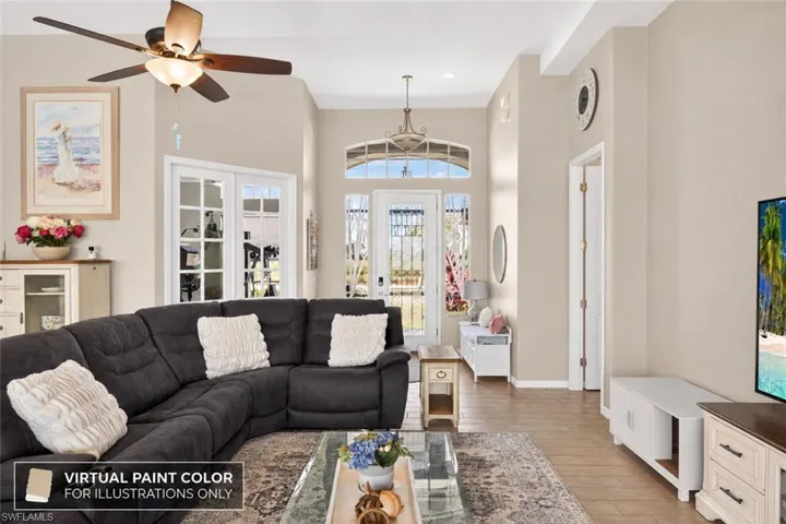 Vaulted ceilings with a ceiling fan, French doors with arched transom windows, and wood-finish flooring