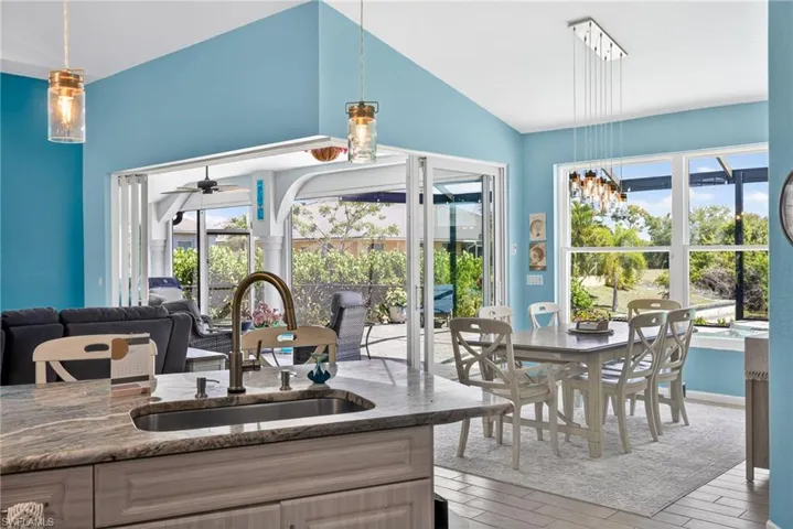 Vaulted ceilings, large windows, folding glass doors, kitchen island with built-in sink, and pendant lighting