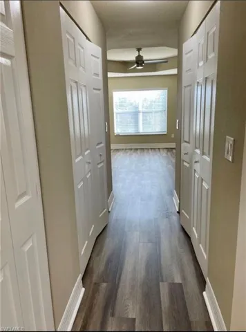 Corridor with baseboards and dark wood-style flooring