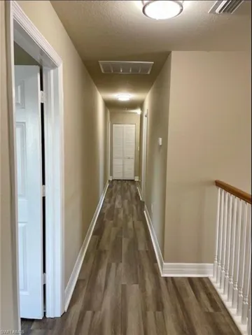 Hallway featuring a textured ceiling and dark wood finished floors
