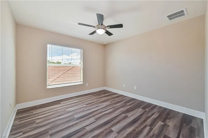 Interior room featuring wood-finish flooring, a window with blinds, a ceiling fan with integrated lighting, and neutral wall tones