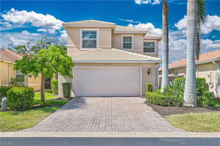 Two-story residence featuring a tile roof, an integrated two-car garage, and a paver driveway