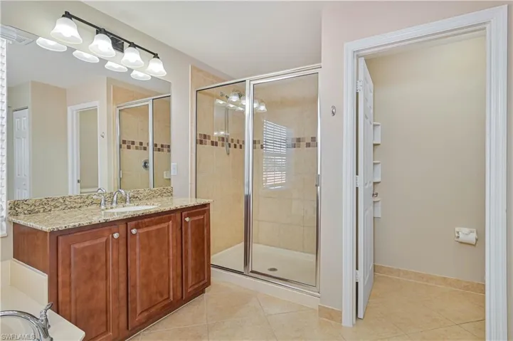 Contemporary bathroom featuring a spacious glass-enclosed shower, a vanity with a granite countertop, and a large mirror