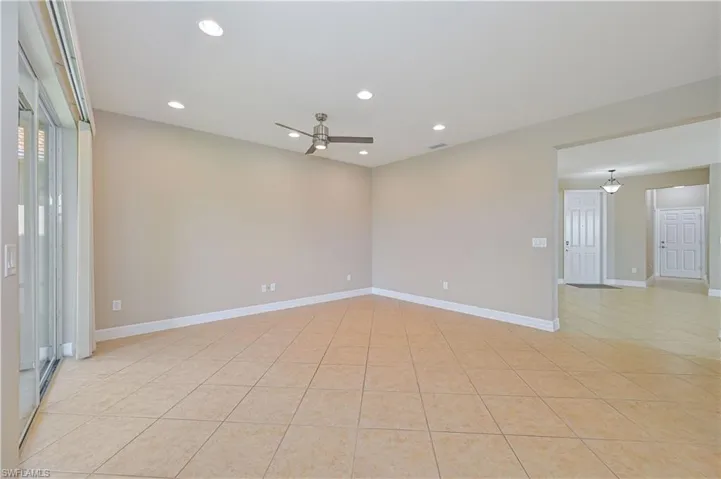 Spacious room featuring tile flooring, a sloped ceiling with recessed lighting, and a ceiling fan