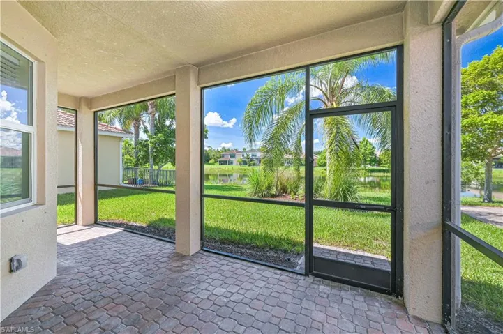 Screened patio with paver flooring, offering expansive views of the water and lush landscaping