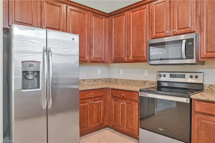 Kitchen featuring rich wood cabinetry, stainless steel appliances, granite-style countertops, and a built-in microwave