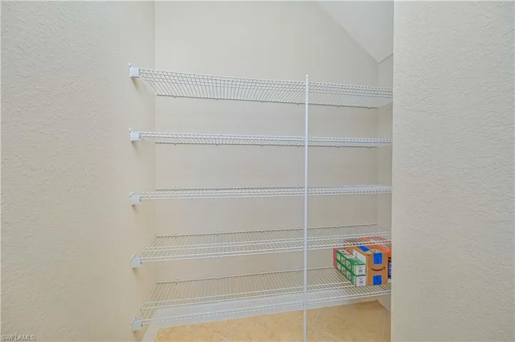 Interior storage space featuring multiple levels of wire shelving and a tiled floor