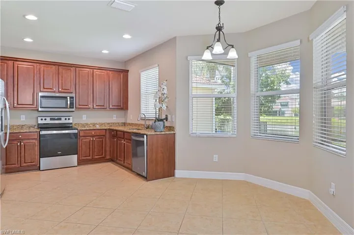 Kitchen featuring wood cabinetry, stainless steel appliances, granite countertops, and tile flooring