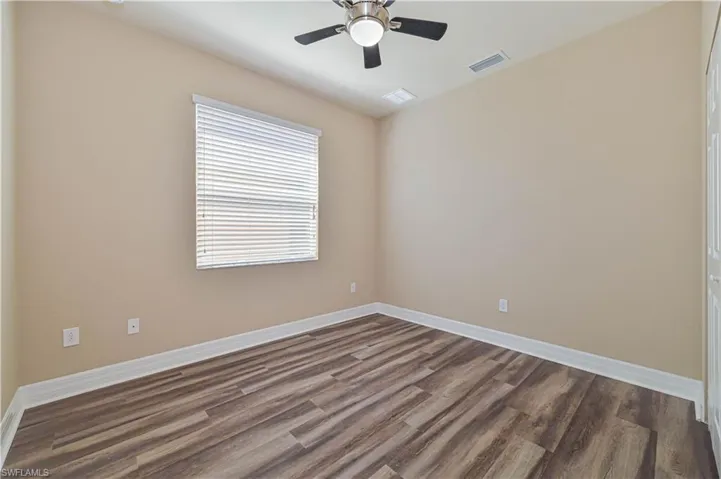Room featuring wood-finish flooring, neutral wall paint, and white baseboards