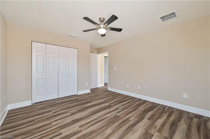 Interior room featuring wood-finish flooring, light neutral-toned walls, and white baseboards