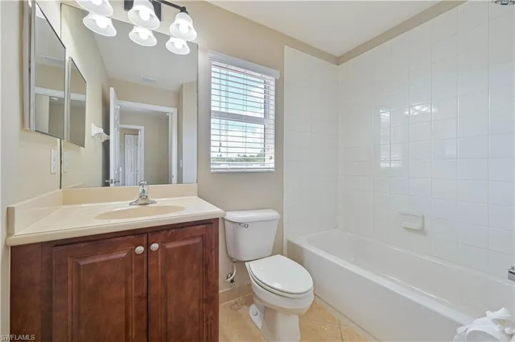 Bathroom featuring a dark wood vanity with a light countertop, a single basin sink, and a large wall mirror