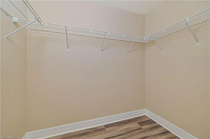 Storage area with light beige walls, white wire shelving, and wood-finish flooring