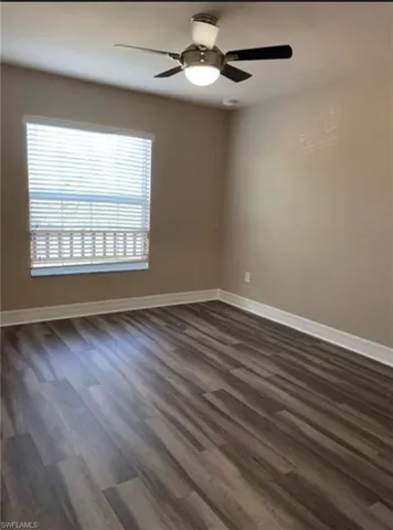 Unfurnished room with ceiling fan and dark wood-style flooring