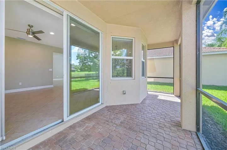 Screened outdoor patio featuring brick paver flooring, stucco exterior, and sliding glass door access to interior space with tile flooring, recessed lighting, and a ceiling fan