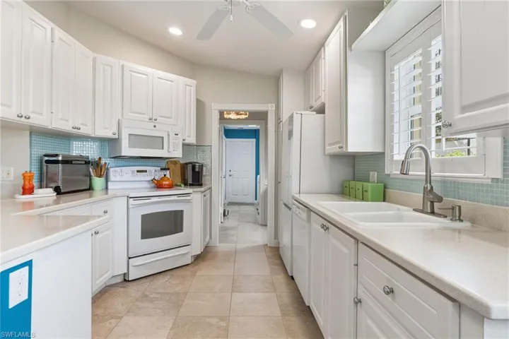 Kitchen with white cabinetry, light countertops, white appliances, decorative backsplash, and recessed lighting