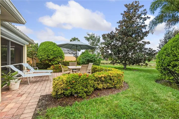 View of grassy yard with a patio and a sunroom