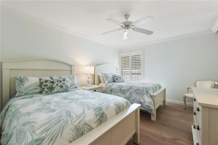 Bedroom featuring crown molding, wood finished floors, and a ceiling fan