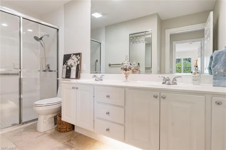 Full bath with double vanity, a shower stall, and light tile patterned floors