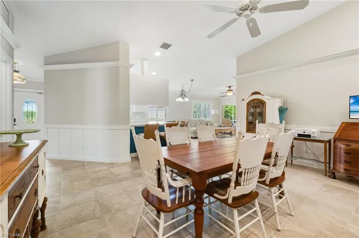 Dining space with wainscoting, a ceiling fan, a chandelier, high vaulted ceiling, and recessed lighting