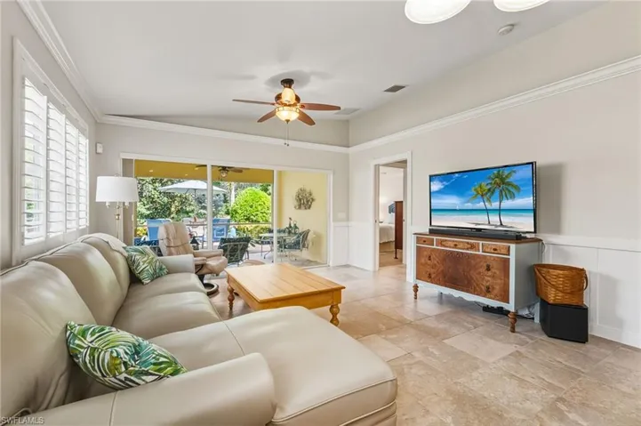 Living area with a wainscoted wall, ceiling fan, ornamental molding, and a decorative wall