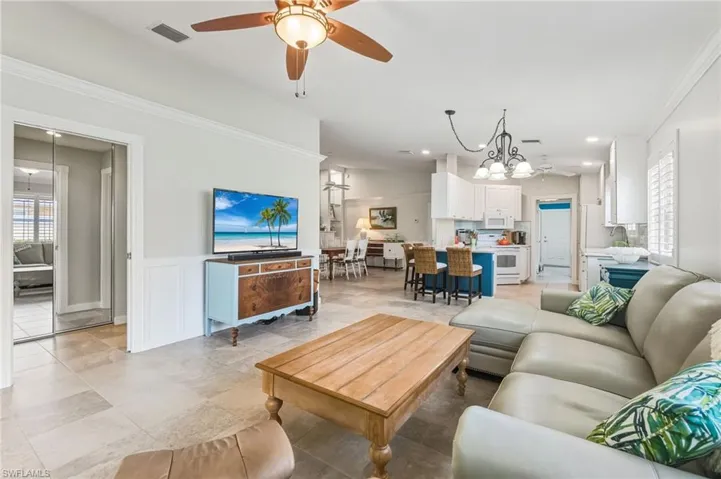 Living room with a ceiling fan, a wainscoted wall, ornamental molding, recessed lighting, and light tile patterned flooring