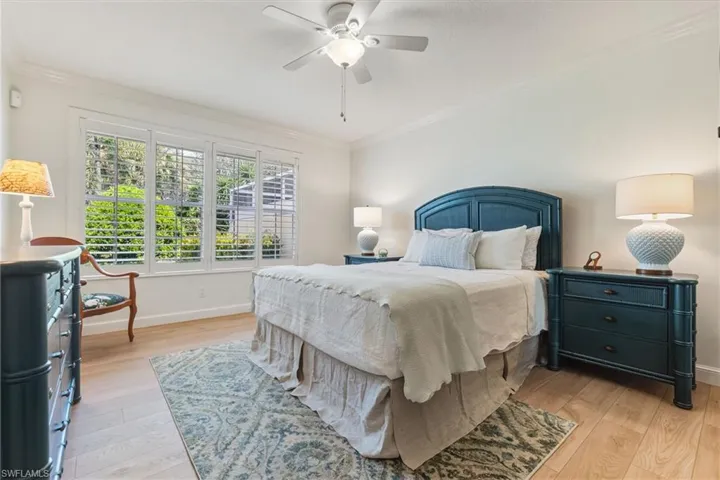 Bedroom with ornamental molding, light wood-type flooring, and ceiling fan
