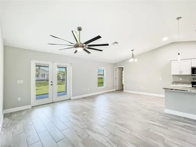Unfurnished living room featuring lofted ceiling, ceiling fan, and plenty of natural light