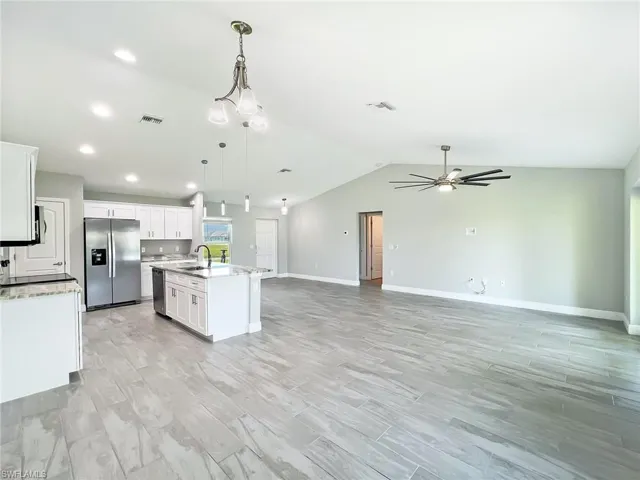 Kitchen with white cabinetry, appliances with stainless steel finishes, sink, and an island with sink