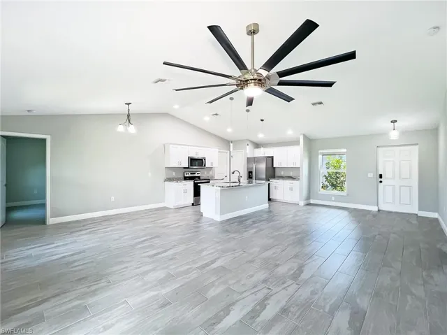 Unfurnished living room featuring light hardwood / wood-style floors, sink, lofted ceiling, and ceiling fan
