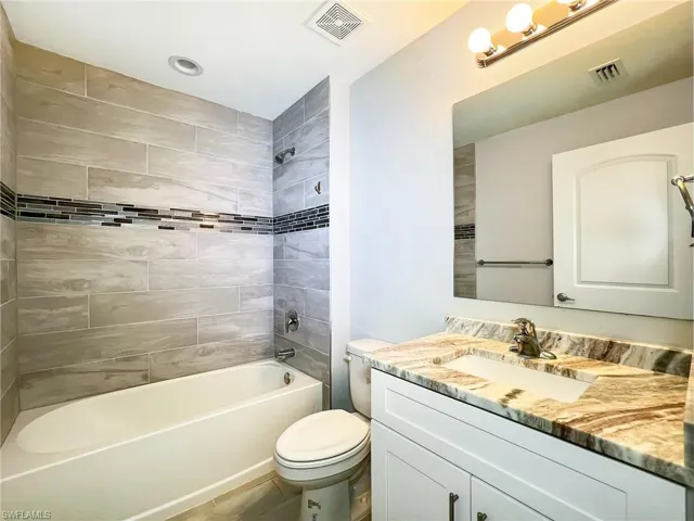 Full bathroom featuring toilet, vanity, and tiled shower / bath