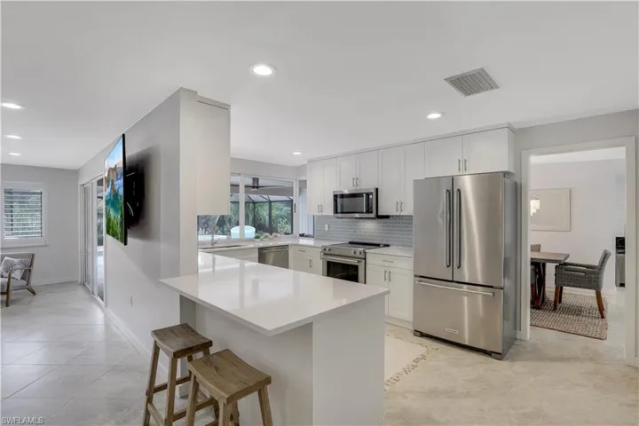 Kitchen with stainless steel appliances, a healthy amount of sunlight, backsplash, and light tile floors