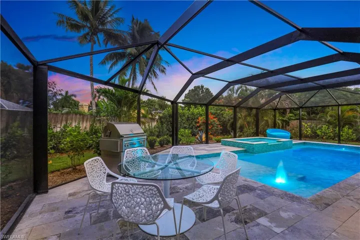 Pool at dusk featuring a patio, a lanai, and an in ground hot tub