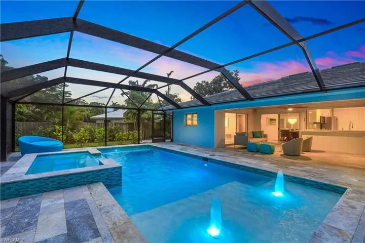 Pool at dusk featuring a patio, sink, glass enclosure, and an in ground hot tub