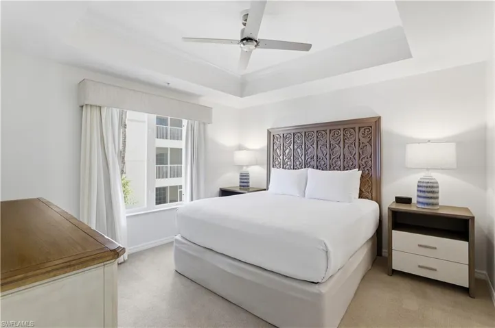 Bedroom with a tray ceiling, a ceiling fan, light colored carpet, and crown molding