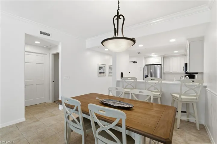 Dining area with ornamental molding, recessed lighting, and light tile patterned flooring