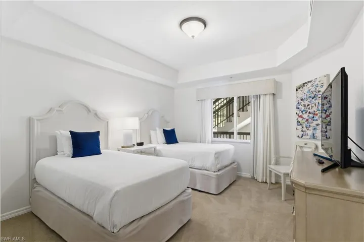 Bedroom with light carpet and a tray ceiling