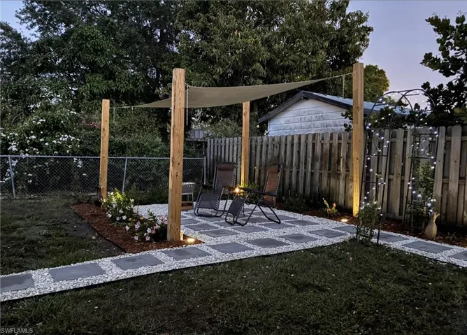 Backyard patio featuring a shade sail structure over a paver and gravel patio