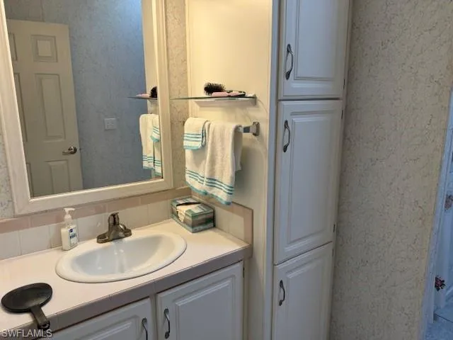 Bathroom featuring vanity and tasteful backsplash
